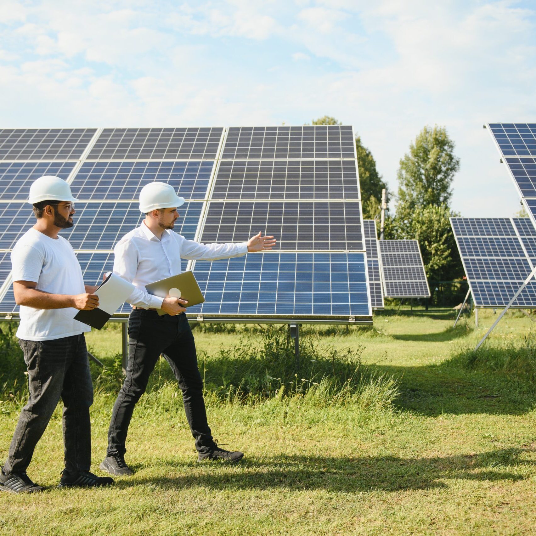 Two engineers or businessmen on the background of solar panels. Renewable energy. Green energy.
